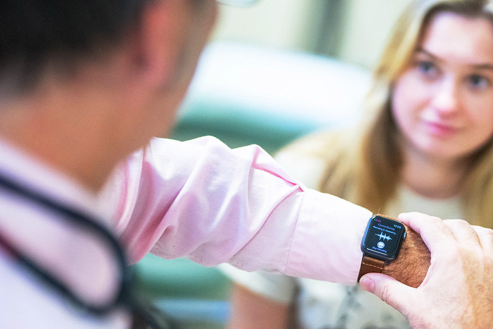 A clinician wearing a smartwatch running CommSense during a patient visit